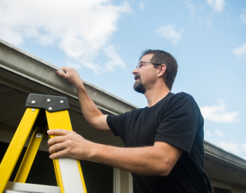 Homeowner inspecting roof in Manitowoc County for storm damage prevention